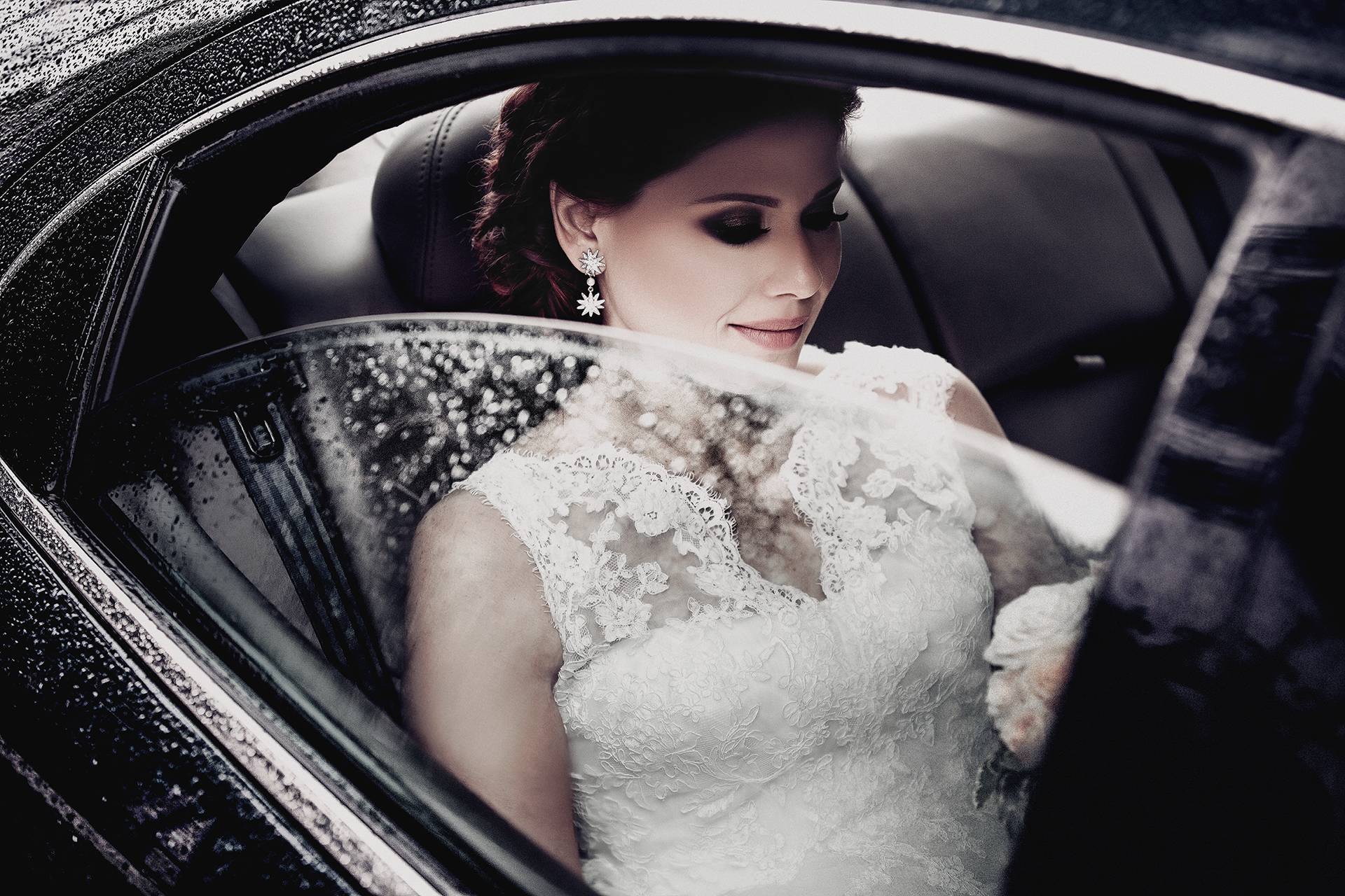 Mireasa în așteptare – fotograf nuntă Transilvania Mireasa elegantă așteaptă în mașină, cu stropi de ploaie pe geam, înainte de nunta ei