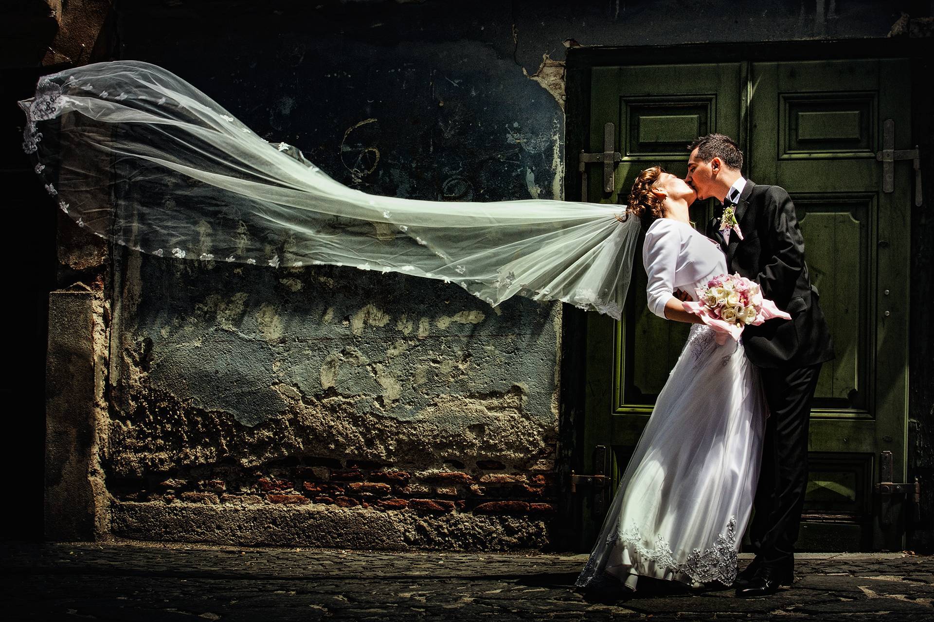 Sărut cu voal în vânt – fotograf nuntă Sibiu Mirii se sărută pasional, iar voalul miresei se ridică în aer la nunta lor