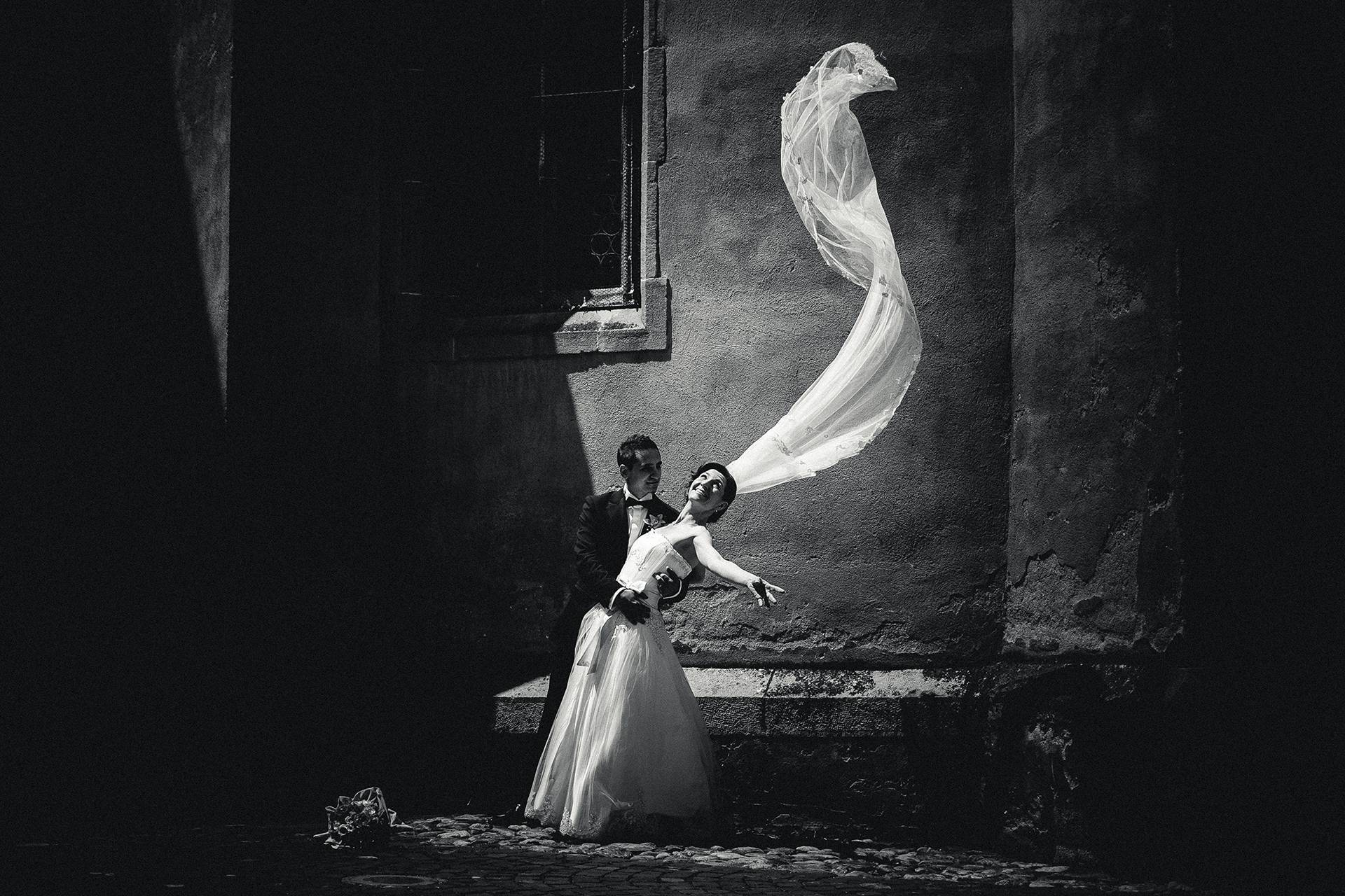 Voal purtat de vânt – fotograf nuntă Transilvania Mirii la sesiunea foto în centrul Sibiului, voalul miresei ridicat de vânt – fotograf nuntă Transilvania