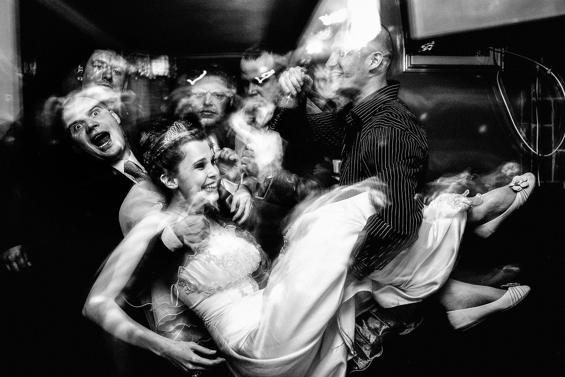 Tradiție cu zâmbet – fotograf nuntă Transilvania Mireasa răpită în brațele invitaților, zâmbind și amuzată de tradiție