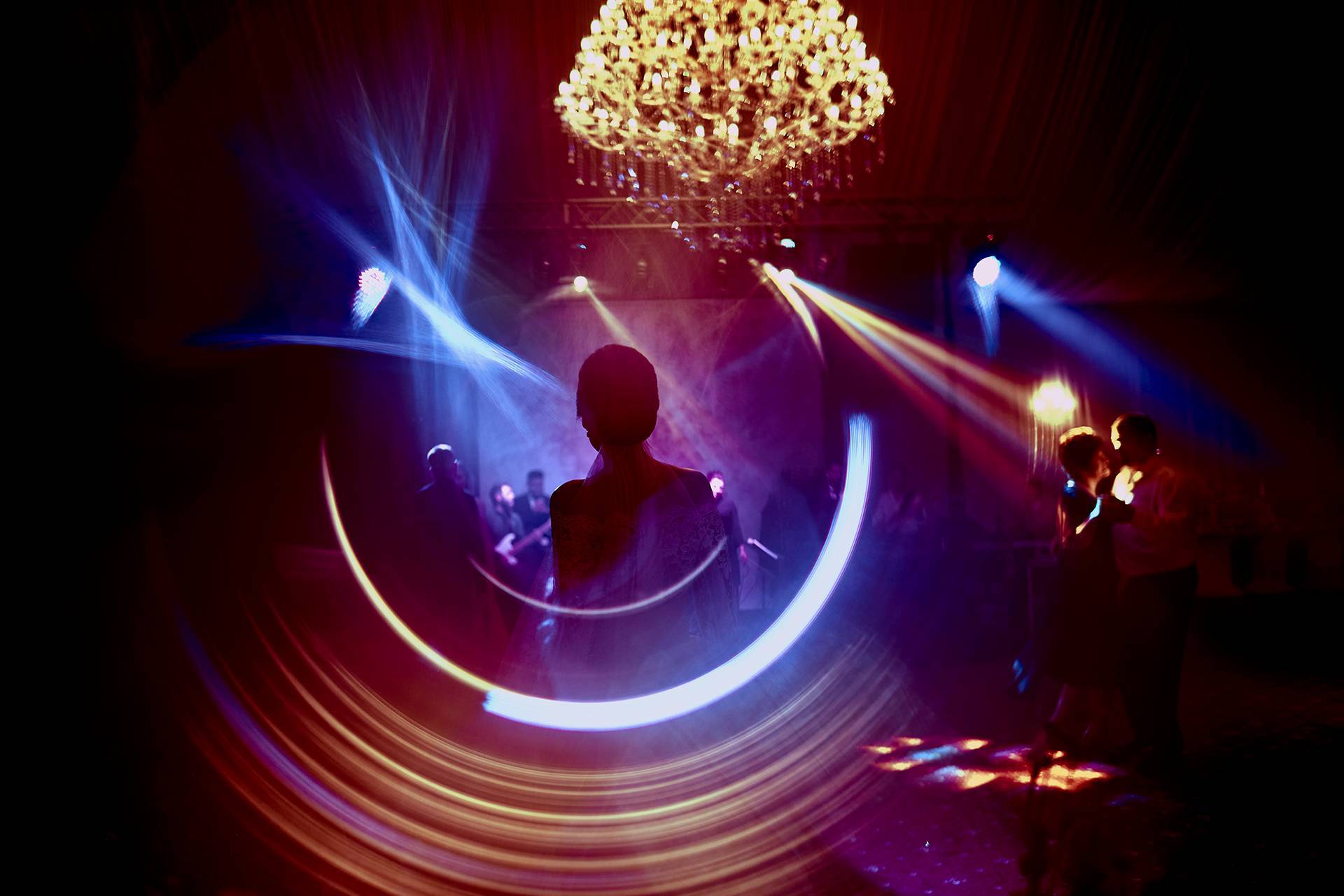 Siluetă vibrantă – fotograf nuntă Transilvania Silueta miresei la petrecere, înconjurată de lumini colorate și reflectoare